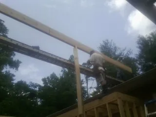 Carpenter setting a ridge beam over a new addition frame — Ice Dam Removal by Roofing Brothers in Hancock