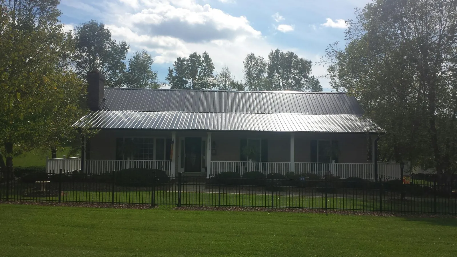 Gray metal roof on a brick ranch with a full width front porch — Gutter Guard Installation work by our crew in Hancock