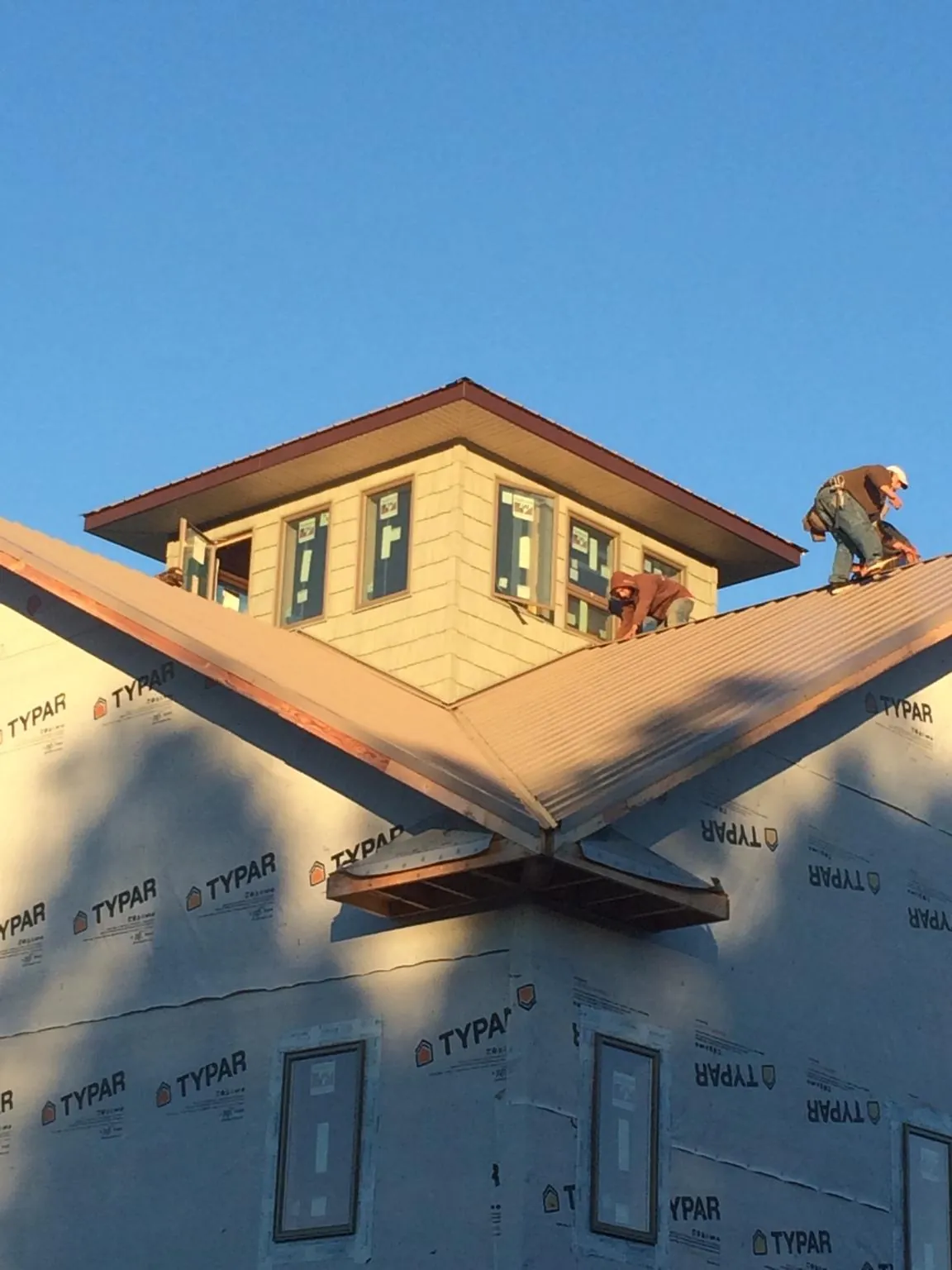 Roofers working around a rooftop cupola on a new metal roof at sunset — Roof Waterproofing in Hancock by Roofing Brothers